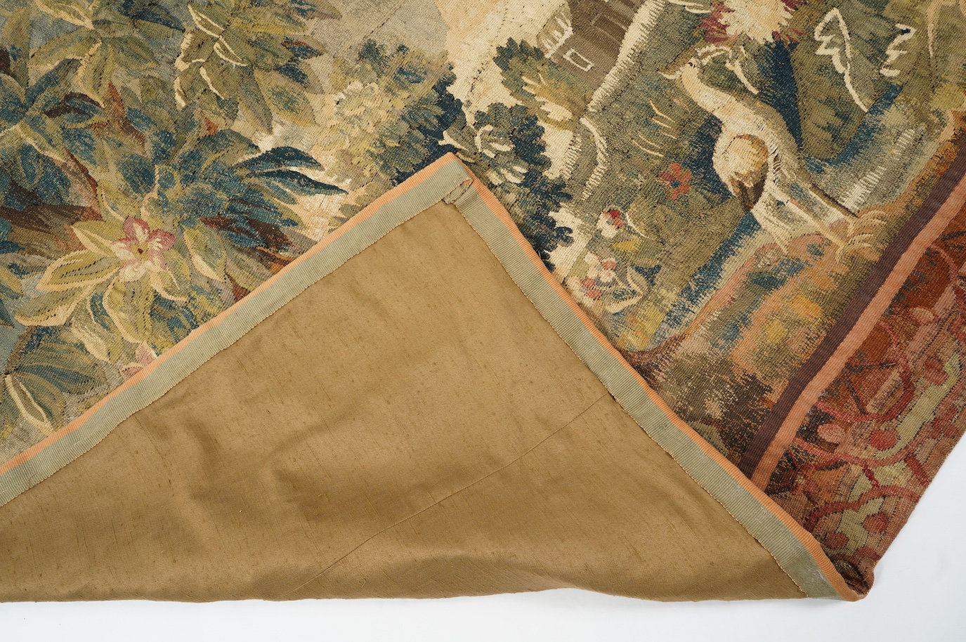 A mid to late 18th century French Aubusson tapestry of a bird, possibly a heron, within a tree lined verdure garden scene to a chateaux, with an ornate rust coloured contrasting tapestry border.201cm x 170 cm. Condition